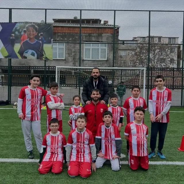 Kırmızı-beyaz formalı akademi takımı ve antrenörleri sahada